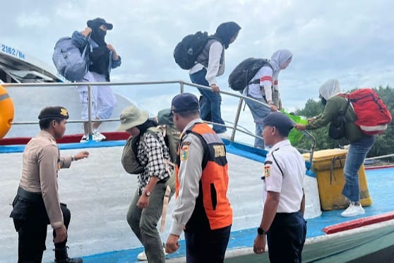 Polisi membantu penumpang di dermaga Pulau Harapan, memastikan keamanan dan kenyamanan.
