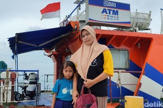 Petugas Teras BRI Kapal melayani nasabah di atas kapal dengan latar lautan, memberikan kemudahan akses perbankan di Pulau Kelapa-Harapan. 📷 detik.com