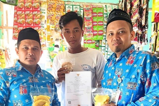 Penyuluh Agama Islam KUA Kecamatan Kepulauan Seribu Selatan, Irvan Dady (kanan) dan Kurnain (kiri) menyerahkan Sertifikat Halal kepada pelaku UMKM UGI RAHAYU di Pari, Kepulauan Seribu Selatan, Rabu (8/7/2026). Sertifikat halal diterbitkan BPJPH sebagai upaya meningkatkan daya saing produk lokal. Foto: Humas Kemenag Kepulauan Seribu.
