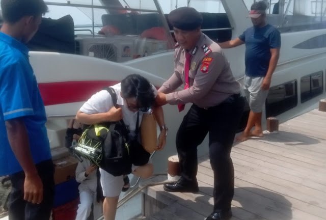 Personel Polres Kepulauan Seribu membantu penumpang turun dari kapal di dermaga sambil mengedukasi masyarakat mengenai Layanan Polisi 110 yang dapat diakses secara gratis selama 24 jam. Foto: Polres Kep. Seribu