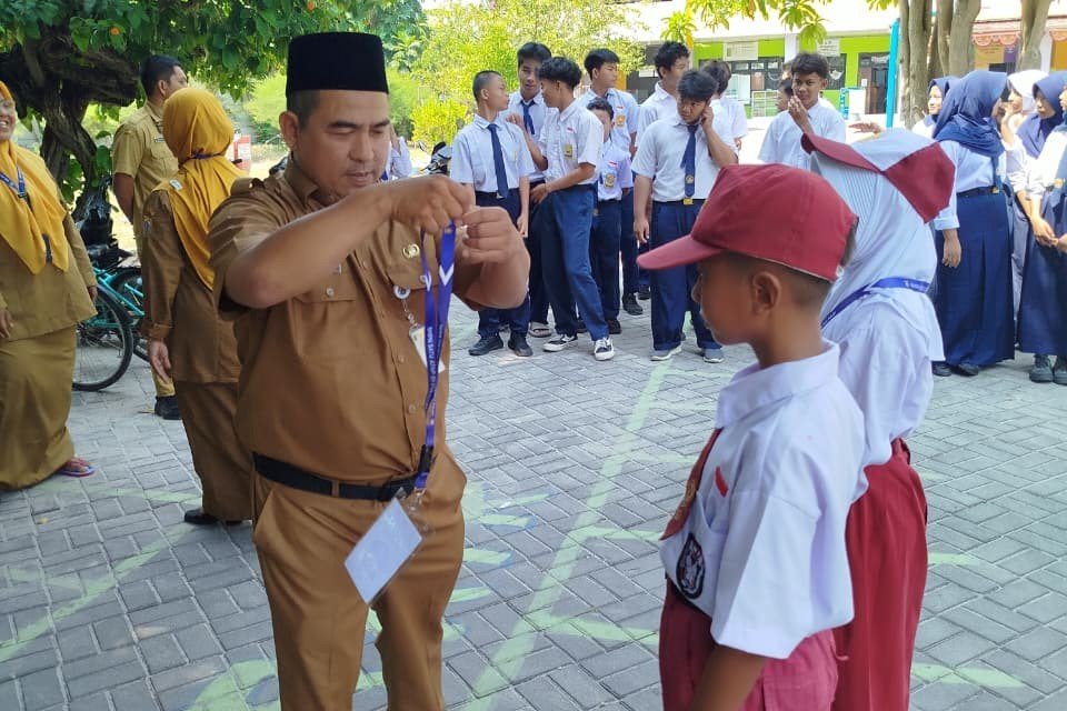 Guru SMPN 01 Satu Atap Pulau Pari menyematkan tanda pengenal siswa baru saat pembukaan MPLS